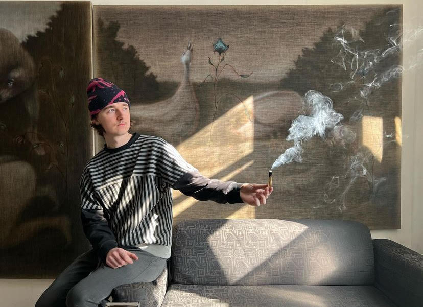 Jędrzej Bieńko siedzący a tle swojego obrazu