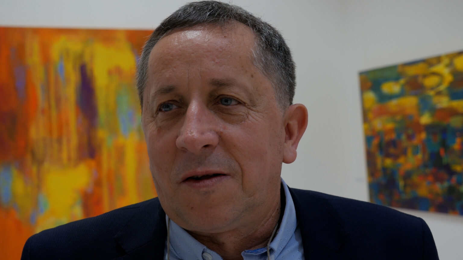 Sylwester Piędziejewski na tle swoich obrazów wernisażu