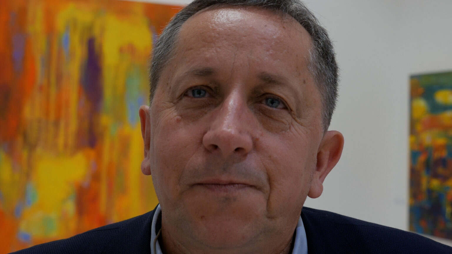 Sylwester Piędziejewski na tle swoich obrazów wernisażu